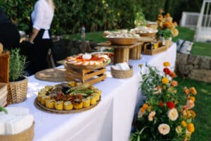 Buffet traiteur extérieur avec légumes grillés, salade caprese et fleurs fraîches lors d'une réception estivale.