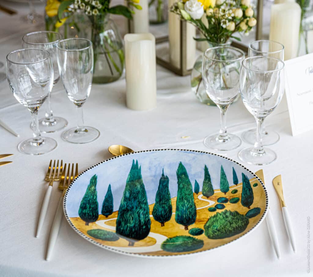 Décoration de Table de Mariage Chic avec Assiette Toscane Art de la table avec assiette peinte de cyprès, couverts or et blanc, verres en cristal et bougies de mariage.
